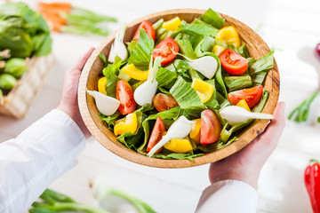 hands holding an healthy fresh vegetarian salad in a bowl