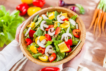hands holding an healthy fresh vegetarian salad in a bowl