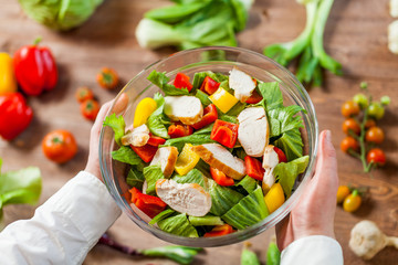 hands holding an healthy checken salad in a bowl