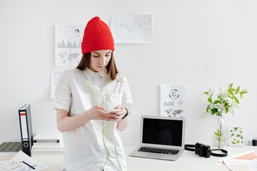 Young female designer working with gadgets and infographics