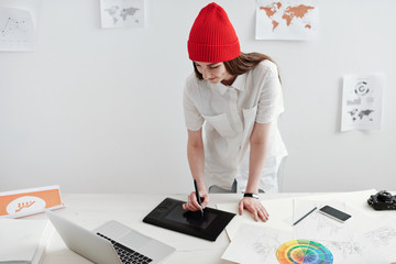 Young female designer using graphic pen and computer