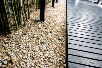Black wooden garden path on white pebbles with bamboo.
