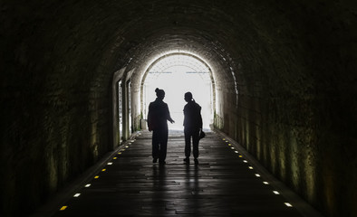 Two girls walking out of a dark corridor.