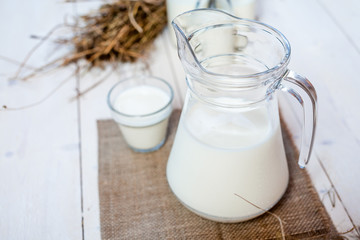jug of milk and glasses of milk on a wooden rustic table.