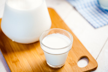 milk and glasses of milk on a wooden rustic table.