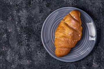 Fresh croissant on dark background.