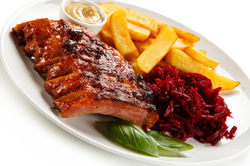 Grilled ribs, French fries and vegetables on white background
