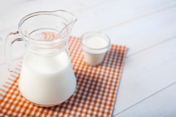 jug of milk and glasses of milk on a wooden rustic table.