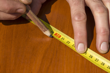 Dłoń robotnika oznacza punkt na desce ołówkiem stolarskim. - obrazy, fototapety, plakaty