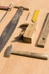 Stare narzędzia stolarskie leżą poukładane na stole.  
