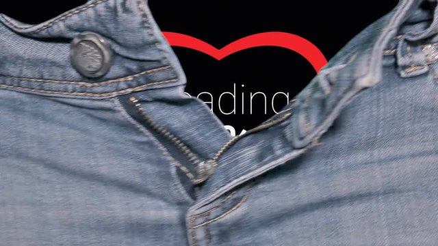 The hands of a woman opening the zipper of a pair of jeans, revealing a loading animation, an increasing progress number (percent) over a red heart being filled up.
