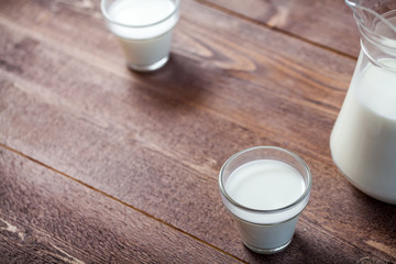 milk and glasses of milk on a wooden rustic table.