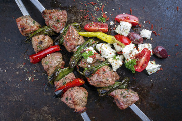 Traditional Greek Souvlaki with Feta and Vegetable as top view on an old rusty board