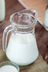 milk and glasses of milk on a wooden rustic table.
