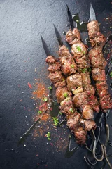 Tuinposter Traditional Russian shashlik on a barbecue skewer as top view on a board © HLPhoto