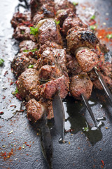 Traditional Russian shashlik on a barbecue skewer as top view on slate slab