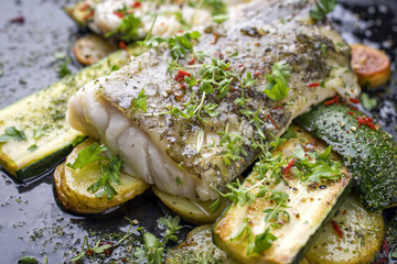 Gebratenes Kabeljau Filet mit Gemüse und Bratkartoffel als top-view auf altem Board