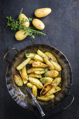 Roast potatoes with herbs as top view in an iron cast pan