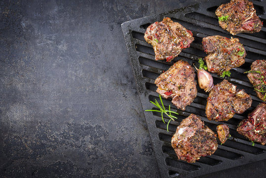 Barbecue t-bone lamb steaks with seasonings as top view on a grillage