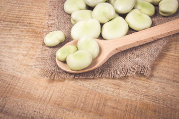 Green fresh broad beans on old wooden table.