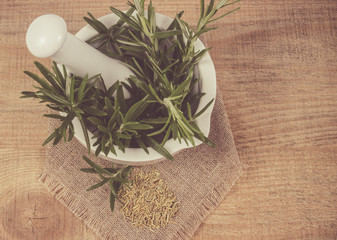 Fresh raw and dry rosemary on rustic background.