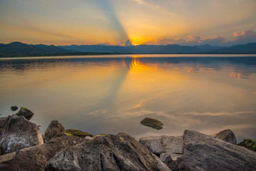 Dramatic view and magic sunbeam at sunset, mountain background. Tranquil panorama landscape of Yang Choom Reservoir, Kui Buri, Prachuap Khirikhan, Thailand.