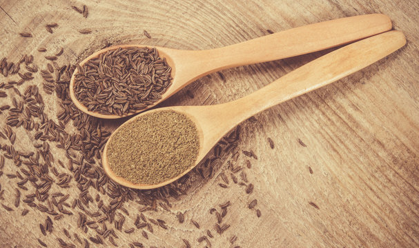 Ground cumin in a spoon and whole cumin