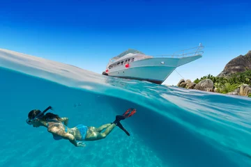 Foto op Plexiglas Small safari boat with snorkeling woman underwater. © Jag_cz