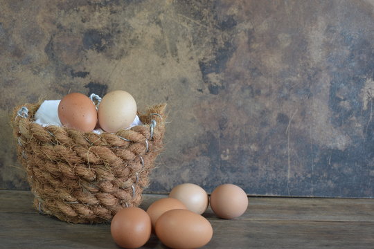 Different color eggs in coconut fiber basket with vintage background