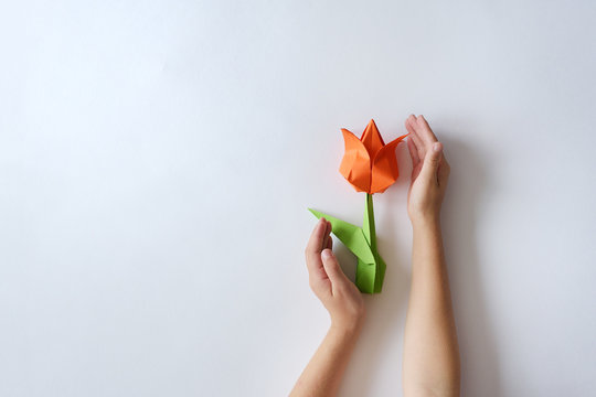 Children's hands do origami from colored paper on white background. lesson of origami