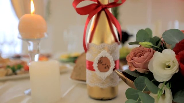 Champagne with the initials of the newlyweds is on the wedding table. Interior of a wedding concept. Blurred background