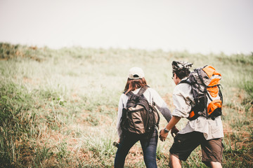 Couple of backpacking hikers going to mountain top and navigating by map paper. Backpackers or Hikers travel concept. Selective focus and vintage tone.