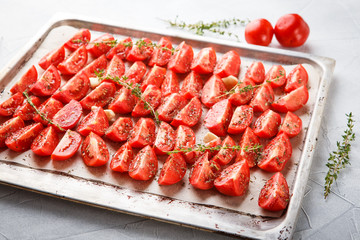Dried tomatoes in baking tray and spatula on blue wooden background
