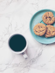 Black coffee and crunchy chocolate chip cookies or biscuits on a decorative plate on marble background. Flat lay. Top view. Copy space
