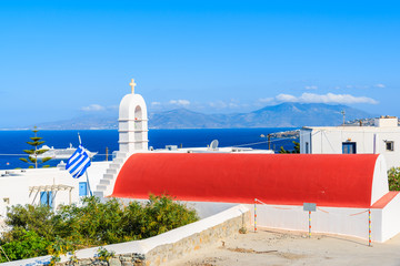 Typical Greek white church with red roof and view of Mykonos port, Mykonos island, Cyclades, Greece © pkazmierczak