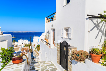 A view of narrow walkway with white houses decorated with flowers in beautiful Mykonos town, Cyclades islands, Greece