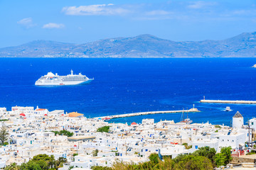 View of white houses of Mykonos town with cruise ship on sea in distance, Mykonos island, Greece © pkazmierczak