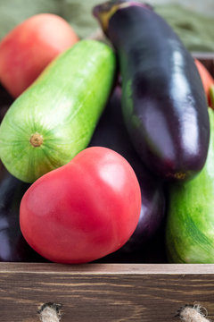 Ingredients for ratatouille or vegetable dish: eggplants, zucchini and tomato in a wooden box, vertical