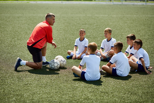 Fototapeta Coach Instructing Junior Football Team