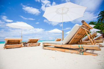 Beach beds and white umbrellas on exotic tropical white sandy beach