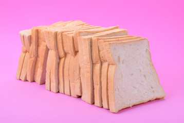 Slice of whole wheat bread on pink background, minimal style.