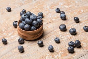 Black ripe berries lie on a wooden saucer and scattered on an old board