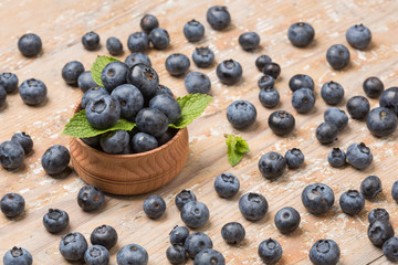 Black ripe berries lie on a wooden saucer and scattered on an old board
