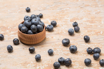 Black ripe berries lie on a wooden saucer and scattered on an old board
