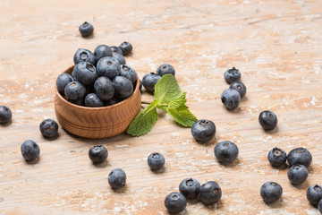 Black ripe berries lie on a wooden saucer and scattered on an old board