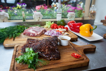 Thick juicy portions of grilled roasted meat on a wooden Board with vegetables