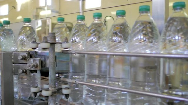 Automatic conveyor line for bottling mineral water in the plastic bottle. Line for PET bottle water. Water factory-bottling pure spring water into bottles. Selective focus.