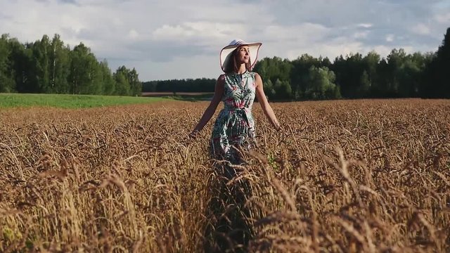 A cute young girl walks by herself in a golden field of wheat