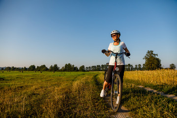 Naklejka na ściany i meble Woman riding bicycle in countryside