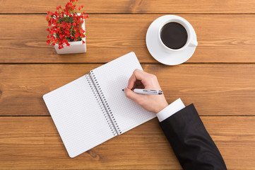 Man taking notes at coffee shop, top view